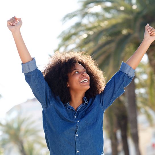 woman celebrating outside with arms in the air