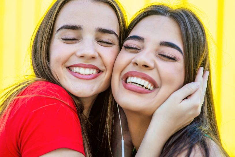 Two young women smiling in a friendly embrace