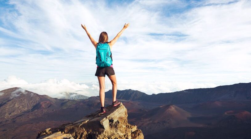 Woman celebrating at the top of a cliff on a hike