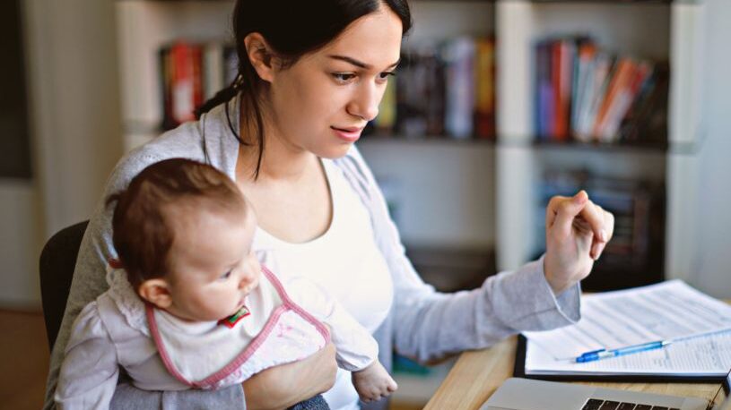 woman taking an online computer literacy course, holding baby
