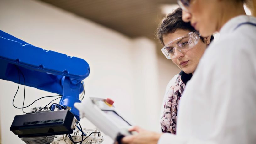 Two woman with goggles evaluating robotic machine